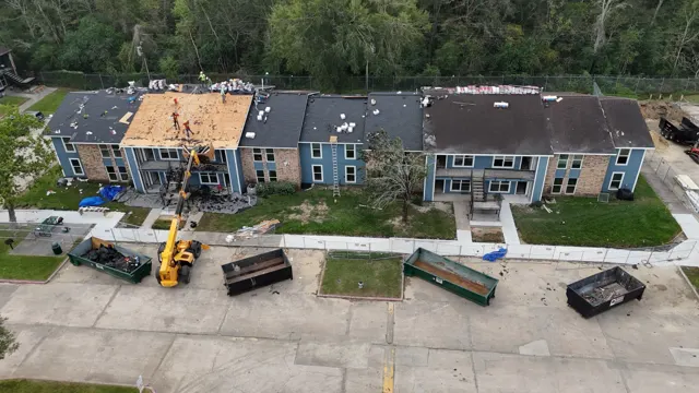 Multi-family apartment reroof in Spring, TX with a telehandler, dumpsters and fenced work zones