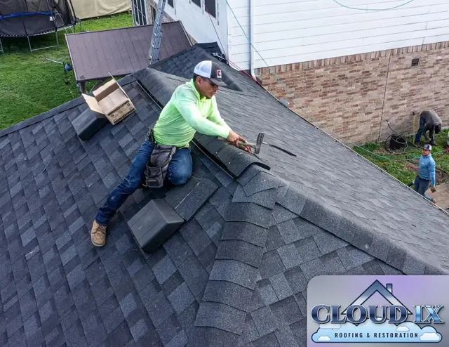 Roofer hand-nailing hip cap shingles next to new roof vents